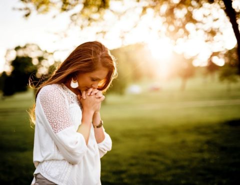 A woman praying in a park